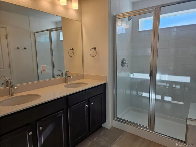 a bathroom with a double vanity sink mirror and shower