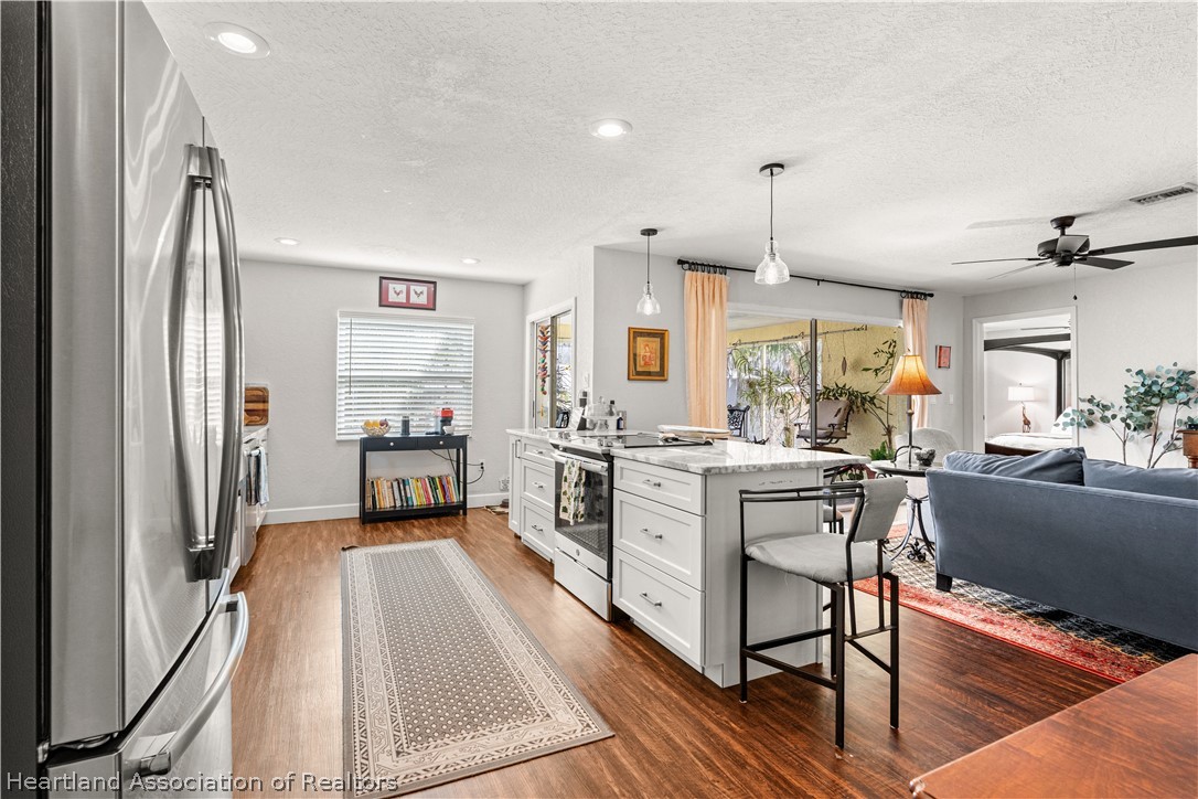 237 Wild Duck Point Lorida, FL 33857 - Photo 17 of 39 a kitchen with stainless steel appliances a stove a sink dishwasher a refrigerator white cabinets and wooden floor next to a window