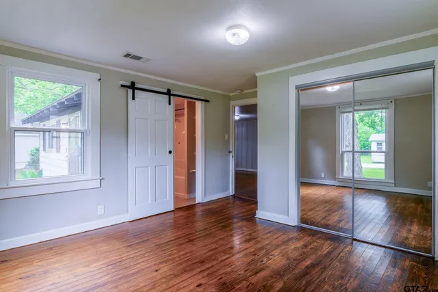 an empty room with wooden floor and windows