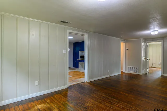 a view of an empty room with wooden floor and closet