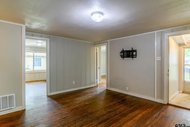 an empty room with wooden floor and windows