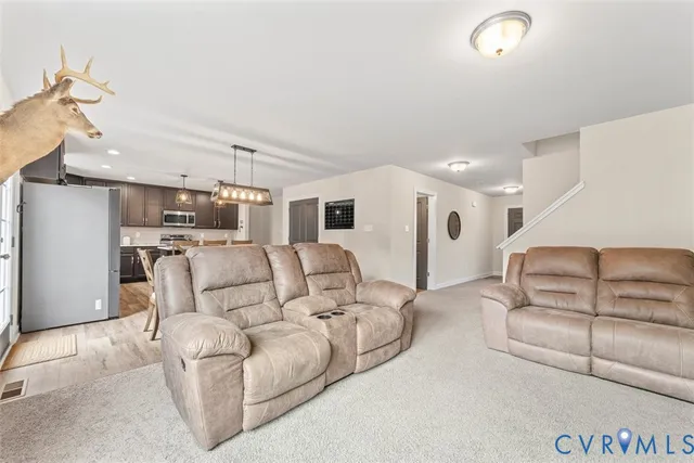 a living room with furniture kitchen view and a chandelier