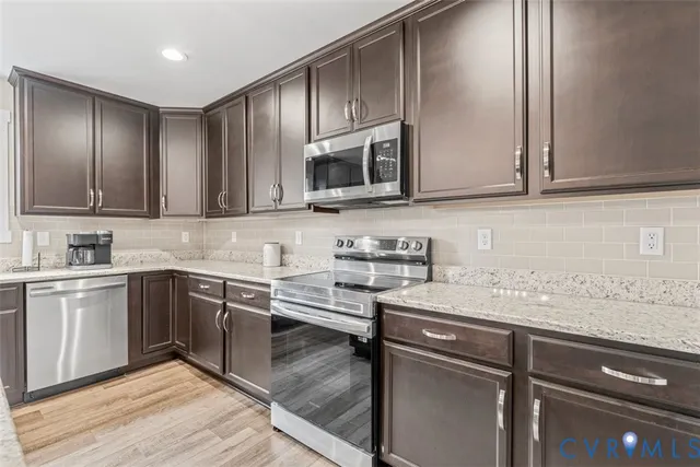 a kitchen with stainless steel appliances granite countertop wooden floors a stove and a refrigerator