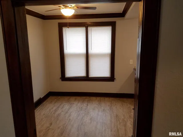 an empty room with wooden floor closet and windows
