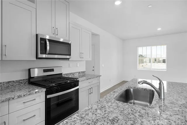 a kitchen with granite countertop a stove and a microwave