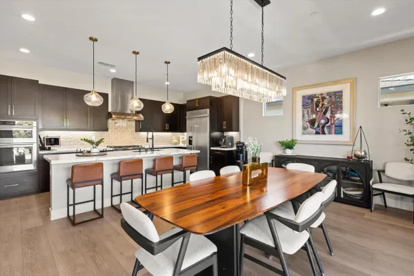 a dining room with wooden floor a chandelier a wooden table and chairs