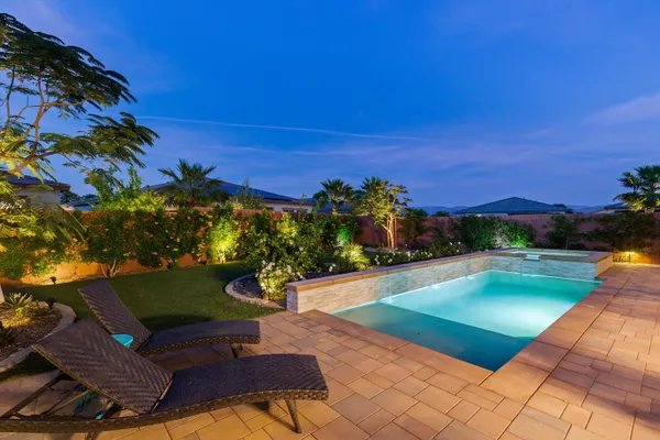 a view of a backyard with lawn chairs under an umbrella