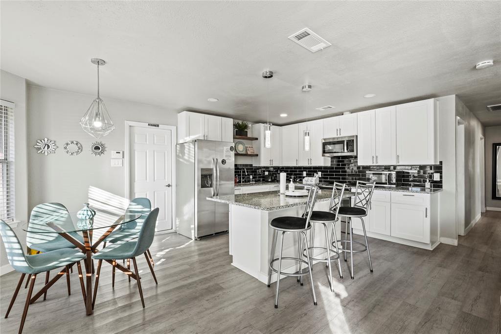 Kitchen with pendant lighting, stainless steel appliances, white cabinets, and a kitchen island