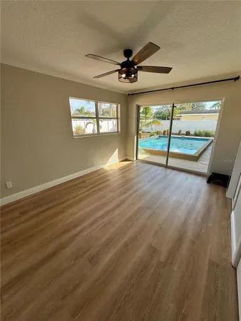 an empty room with wooden floor fan and windows