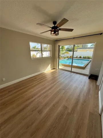 an empty room with wooden floor fan and windows