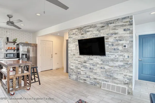 a living room with stainless steel appliances wooden floor and a fireplace