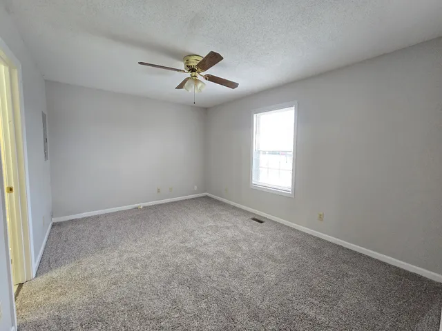 an empty room with a window and a fan