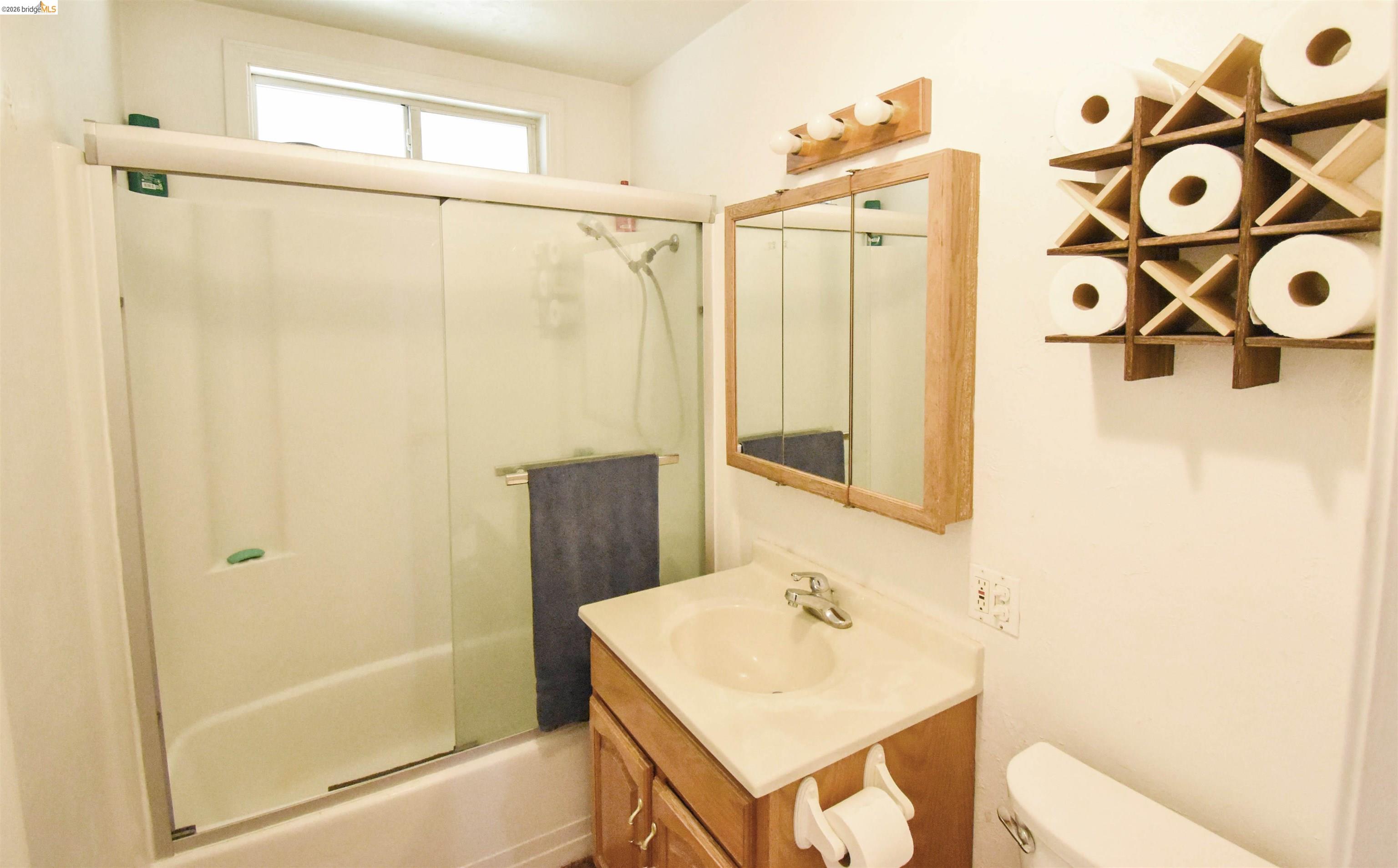 13904 Tuolumne Road Sonora, CA 95370 - Photo 23 of 44 Bathroom featuring a bathtub with sliding glass doors, a vanity with a cultured marble countertop, a mirrored medicine cabinet, and an overhead window