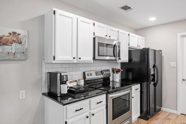 a kitchen with stainless steel appliances granite countertop a stove a refrigerator and a microwave