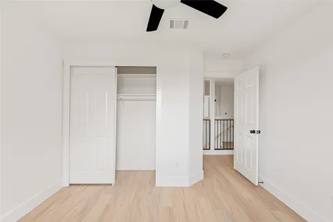 an empty room with wooden floor cabinet and windows