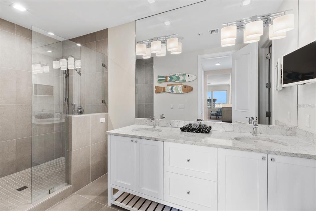 1111 Ritz Carlton Drive, Unit 1803 Sarasota, FL 34236 - Photo 44 of 65 a bathroom with a sink a large mirror and shower