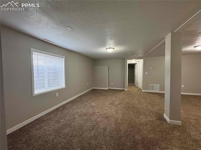 4420 Galley Road Colorado Springs, CO 80915 - Photo 15 of 20 Basement family room featuring carpet floors, a textured ceiling, and baseboards