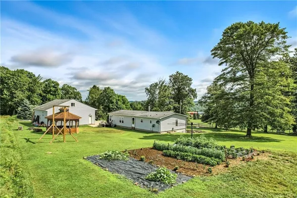 a view of a garden with a bench in front of the house