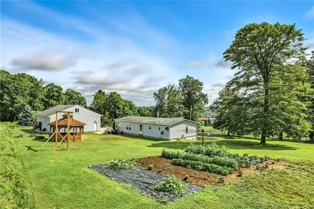 a view of a garden with a bench in front of the house