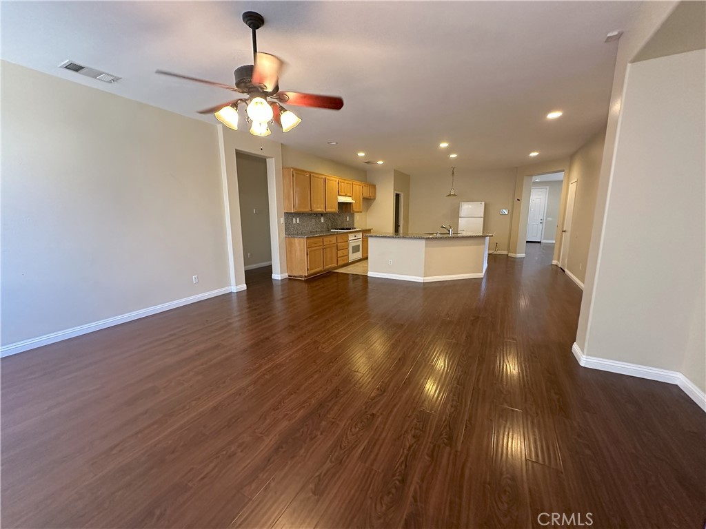 13352 Pleasant View Street Oak Hills, CA 92344 - Photo 4 of 13 a view of an empty room and kitchen with wooden floor