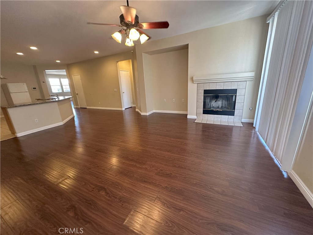 13352 Pleasant View Street Oak Hills, CA 92344 - Photo 5 of 13 an empty room with wooden floor fireplace and windows