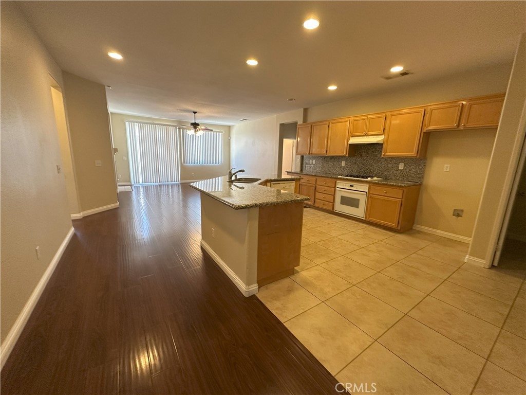 13352 Pleasant View Street Oak Hills, CA 92344 - Photo 7 of 13 a kitchen with stainless steel appliances granite countertop a sink and a stove top oven with wooden floor