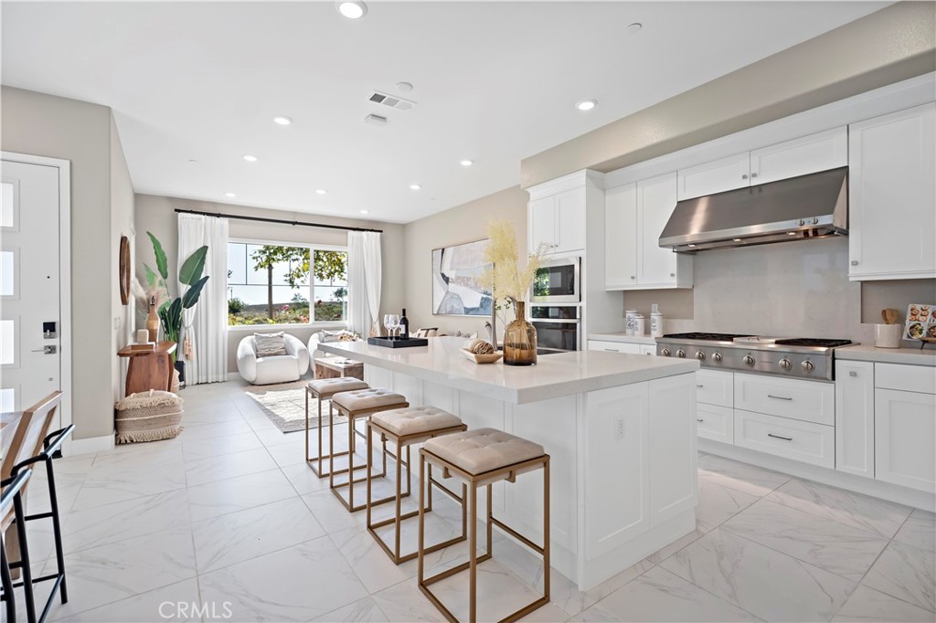 168 Perspective Irvine, CA 92618 - Photo 14 of 62 a large white kitchen with granite countertop a stove a sink a dining table and chairs
