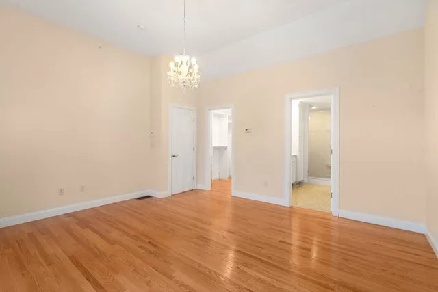 a view of empty room with wooden floor and chandelier
