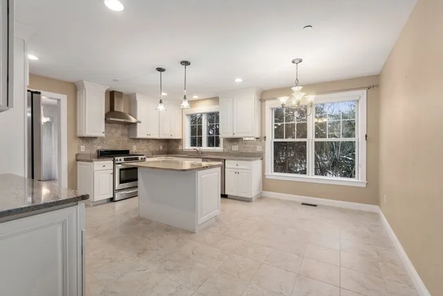 a large kitchen with kitchen island a counter top space a sink stainless steel appliances and cabinets