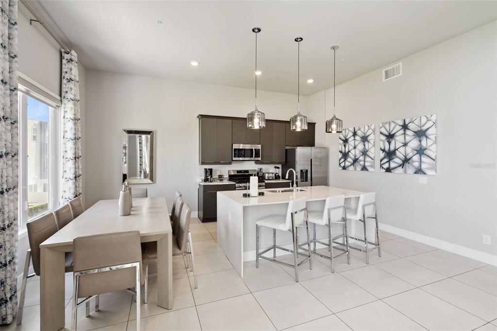 7770 Sandy Ridge Drive, Unit 223 Reunion, FL 34747 - Photo 7 of 51 a kitchen with stainless steel appliances kitchen island granite countertop a dining table chairs and a white refrigerator