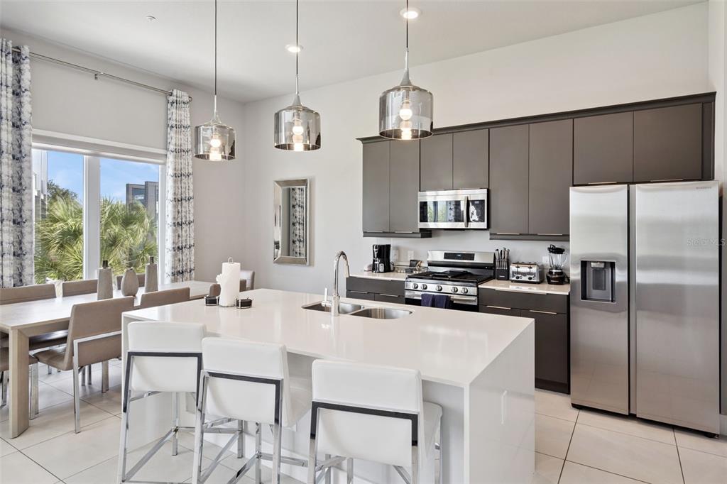 7770 Sandy Ridge Drive, Unit 223 Reunion, FL 34747 - Photo 9 of 51 a kitchen with stainless steel appliances a table chairs refrigerator and microwave