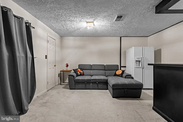 a living room with furniture wooden floor and a refrigerator