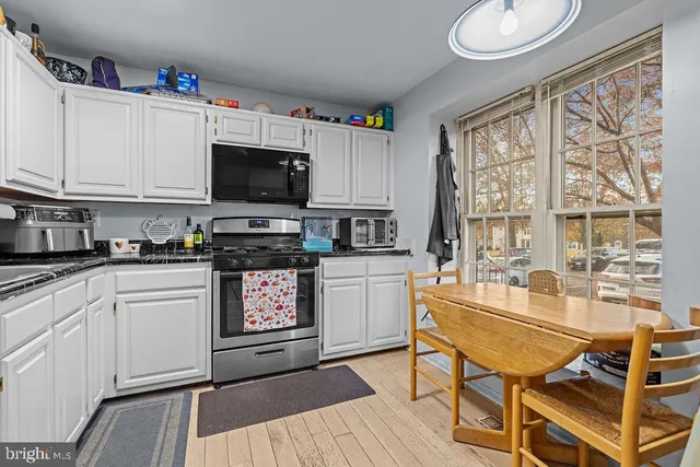 a kitchen with granite countertop a stove a sink dishwasher and a microwave with wooden floor