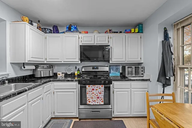 a kitchen with granite countertop a sink stainless steel appliances and cabinets