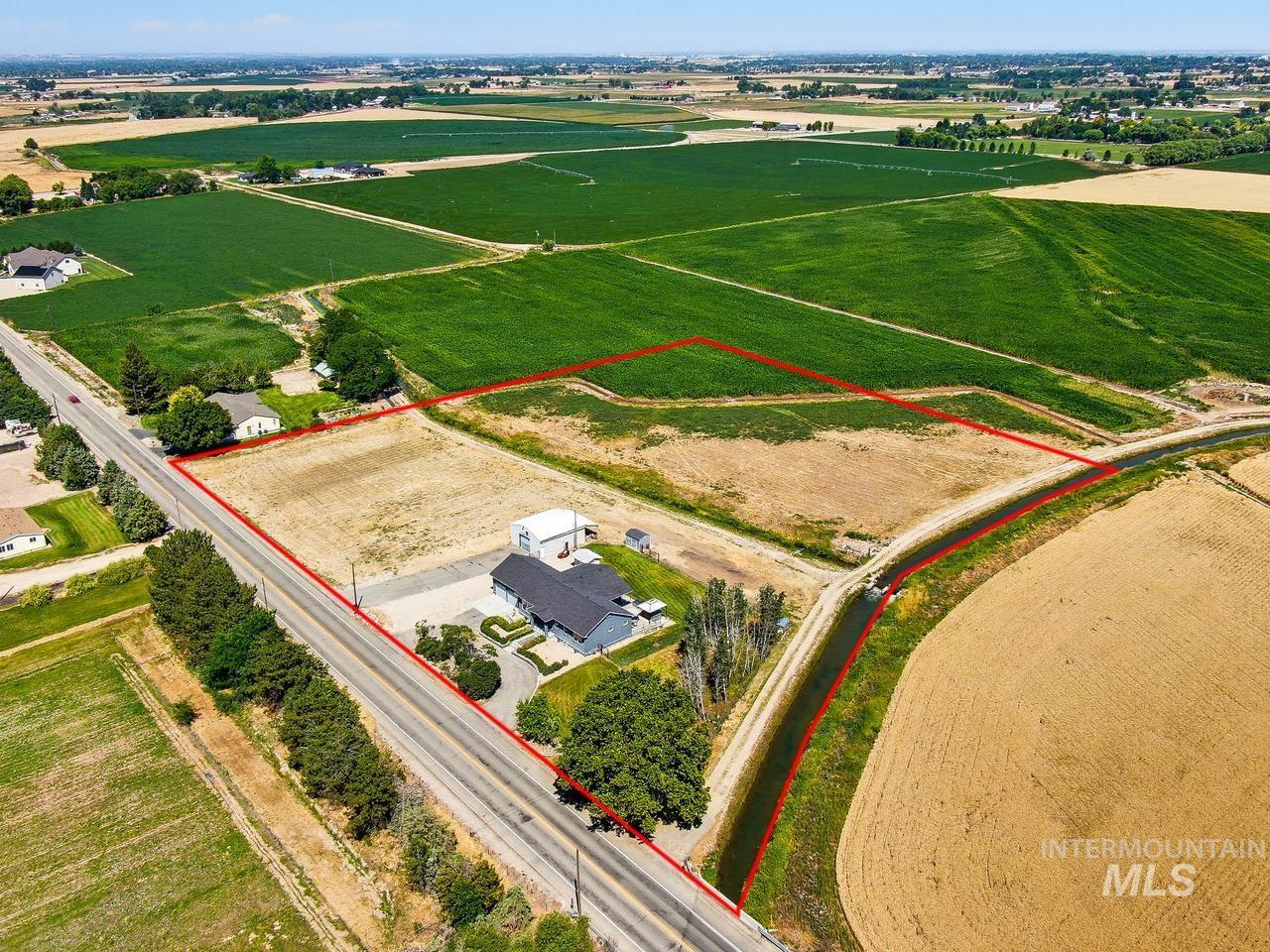 4950 West Columbia Road Nampa, ID 83687 - Photo 48 of 50 Expansive rural property featuring a modern residence with a dark gray roof, a large concrete parking area, and mature landscaping