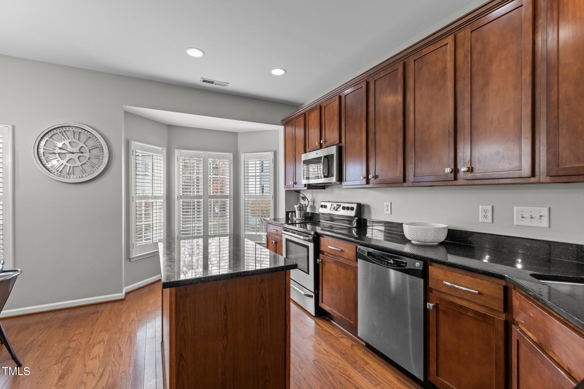 1667 Snow Mass Way Durham, NC 27713 - Photo 7 of 33 a kitchen with stainless steel appliances granite countertop a stove a sink dishwasher and a microwave oven with wooden floor
