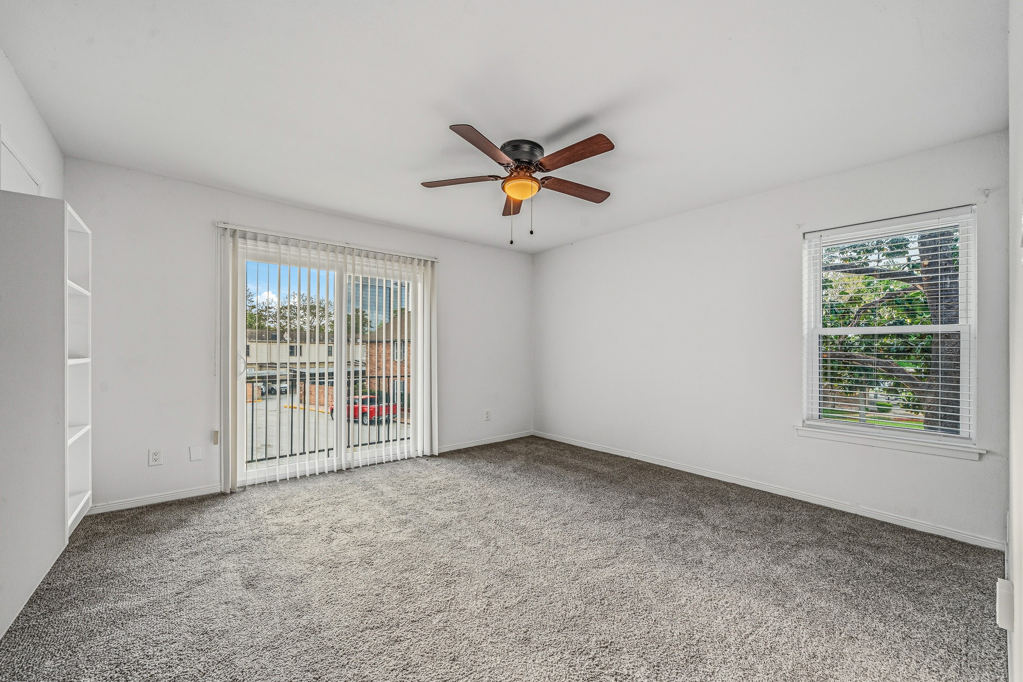 830 Threadneedle Street, Unit 240 Houston, TX 77079 - Photo 22 of 33 Bright and spacious room with neutral carpet, a ceiling fan, and ample natural light from large windows and sliding glass doors. Perfect for a cozy living area or bedroom.