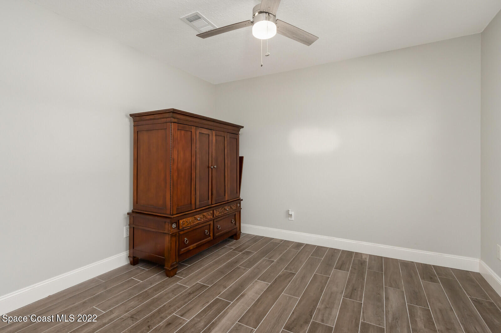 210 Sand Pine Road Indialantic, FL 32903 - Photo 23 of 45 an empty room with wooden floor fan and windows