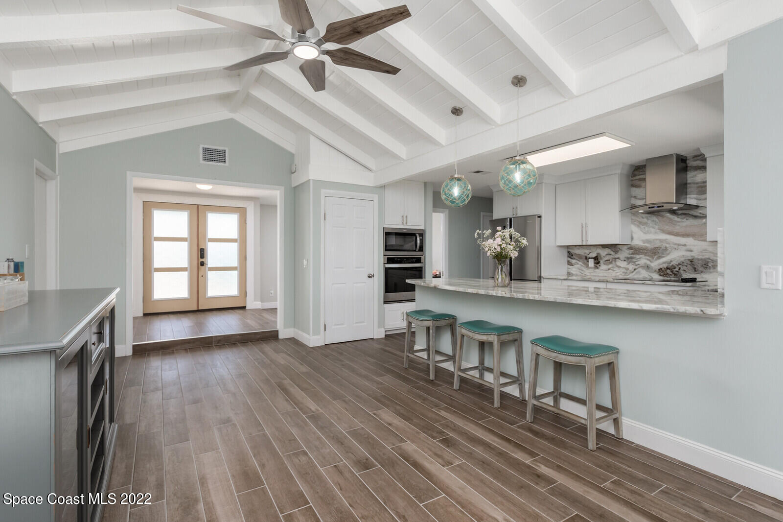 210 Sand Pine Road Indialantic, FL 32903 - Photo 4 of 45 an open kitchen with a sink dishwasher a dining table and chairs with wooden floor