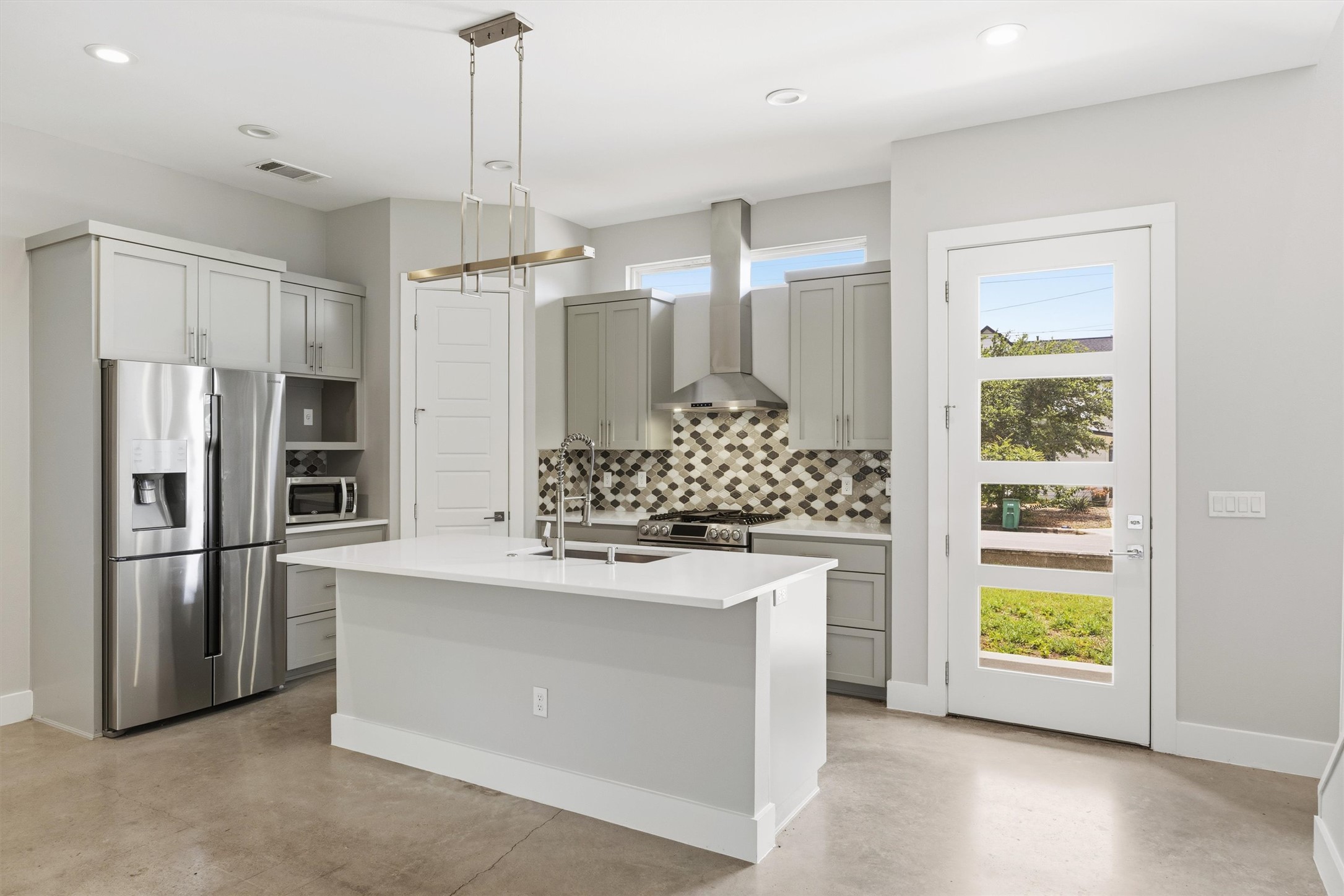 1210 Stobaugh Street, Unit B Austin, TX 78757 - Photo 33 of 40 A sleek island kitchen with gray cabinetry and stainless steel appliances awaits culinary creations.