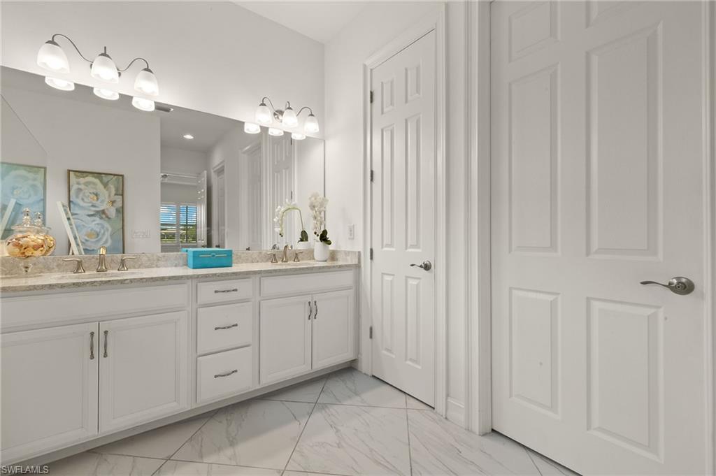 14809 Windward Lane Naples, FL 34114 - Photo 24 of 50 a spacious bathroom with a double vanity sink a mirror a lamp and a bathtub