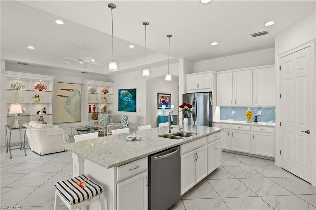 14809 Windward Lane Naples, FL 34114 - Photo 9 of 50 a kitchen with a sink dishwasher and white cabinets with wooden floor