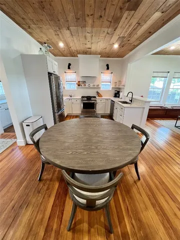 a room with wooden floor pool table and chairs