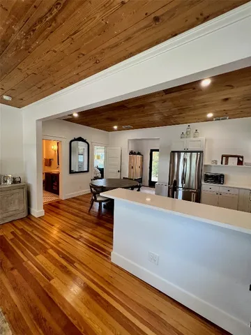 a living room with couches and kitchen view with wooden floor