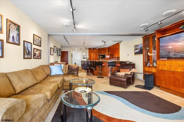 a living room with furniture kitchen view and a wooden floor