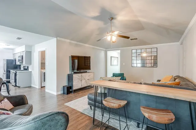 a living room with stainless steel appliances kitchen island granite countertop furniture and a flat screen tv
