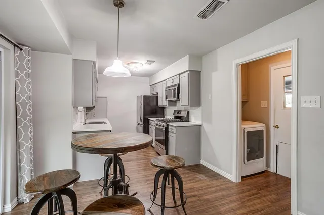 a kitchen with stainless steel appliances a table and chairs in it