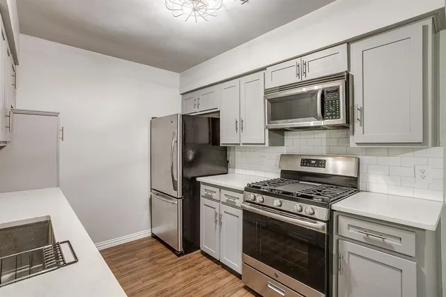 a kitchen with stainless steel appliances white cabinets a stove top oven a sink and dishwasher