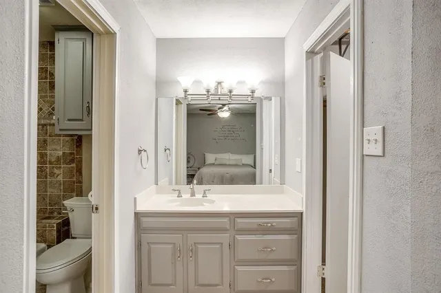 a bathroom with a granite countertop sink a toilet and a mirror