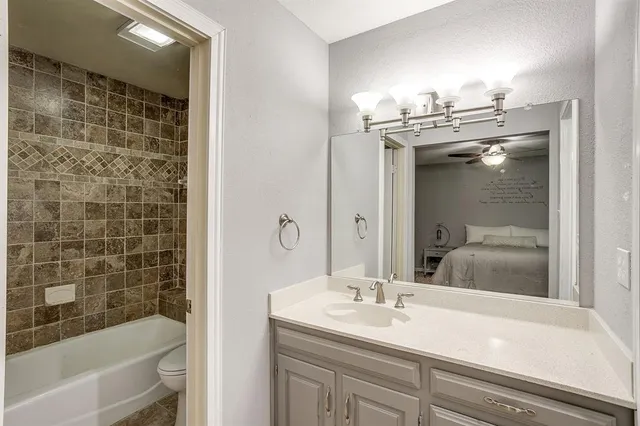 a bathroom with a granite countertop sink a toilet and shower